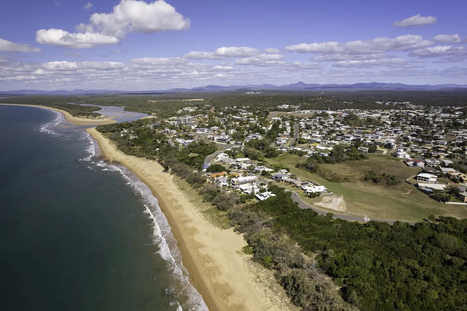 Aerial view of the long sandy beach and coastal homes at Tannum Sands